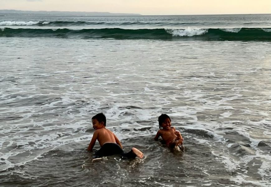 Two children playing in the shallow waves